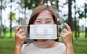 An asian woman putting on a protective face mask for Healthcare concept