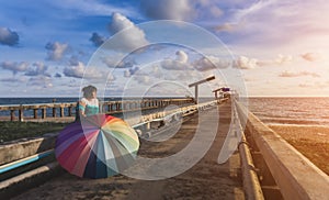 Asian woman and rainbow umbrella on the sea bridge