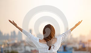 Asian woman raised hands up in the air over city background while standing at outdoor