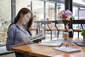 Asian woman reading a book in coffee shop.