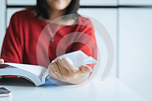 Asian woman reading a book sitting feelling happy and relax on table