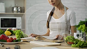 Asian woman reading cooking book and choosing dinner recipe, healthy food habit