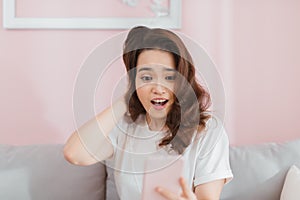 Asian woman reading shocking text at home in the living room