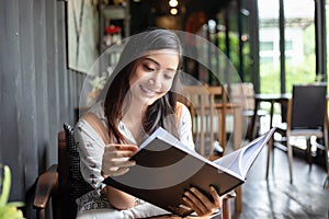 Asian women reading and smiling and happy Relaxing in a coffee shop after working in a successful office