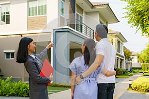 Asian woman Real estate broker agent showing a house detail in her file to the young Asian couple lover looking and interest to