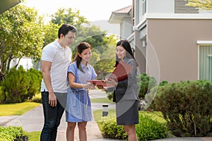Asian woman Real estate broker agent showing a house detail in her file to the young Asian couple lover looking and interest to