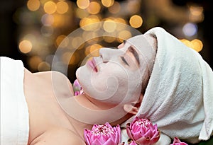 Asian woman receiving clay facial mask in spa beauty salon