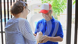 Asian woman receiving container box from delivery man at home