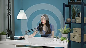 Asian woman recording online podcast with microphone on camera
