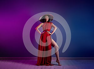 asian woman in red cape and asian hat posing on bright neon background