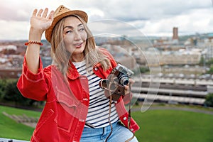 asian woman in a red jacket sitting in front of the city Sheffield and take photos on great summer day