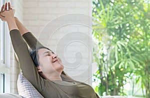 Asian woman relax on sofa in her free time in room background