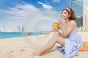 Asian woman is relaxing on the beach in Dubai and drinking a delicious drink and coconut cocktail . Holiday and beverage