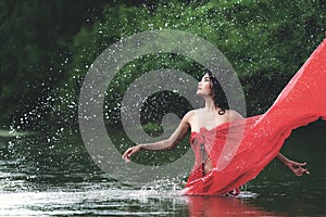 Asian woman relaxing and enjoying playing with water and splash at tropical exotic river with turquoise amazing color water in bea