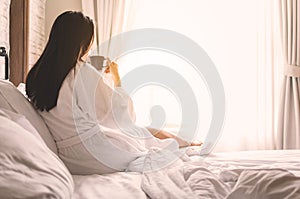 Asian woman relaxing in the hotel room, drinking morning coffee