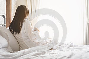 Asian woman relaxing in the hotel room, drinking morning coffee