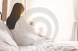 Asian woman relaxing in the hotel room, drinking morning coffee