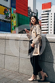 Asian woman replying emails on mobile phone