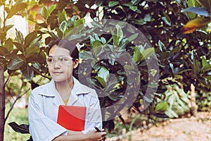 Asian woman researcher standing and examining plant with study data in the garden