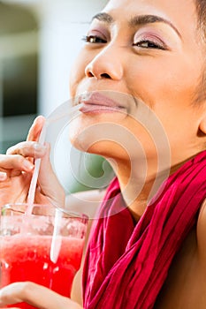 Asian woman in restaurant drinking