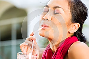 Asian woman in restaurant drinking