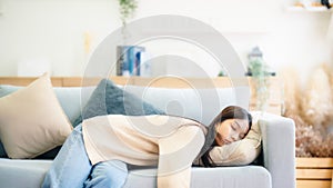 Asian woman resting at home on couch, feeling exhausted after work