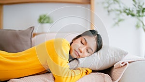 Asian woman resting at home on couch, feeling exhausted after work