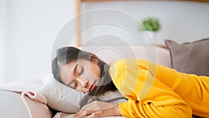 Asian woman resting at home on couch, feeling exhausted after work