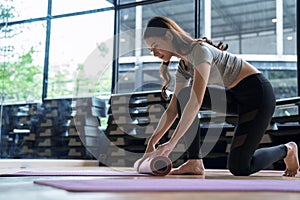 Asian woman rolls her mat after studying yoga