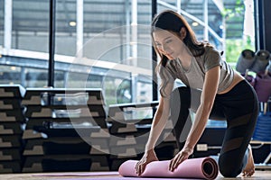 Asian woman rolls her mat after studying yoga