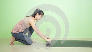 Asian woman rolls yoga mat