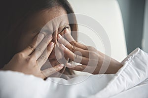 Asian woman rubbing eyes with her hands on her bed. photo