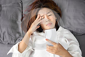 Asian woman rubbing her eyes tired from watching series from smart phone  late at night