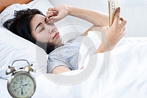 Asian woman rubbing her itchy and tired eye watching too much on mobile phone screen