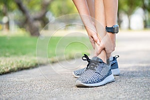 Asian woman runner has ankle sprain, legs have problem. woman hand massaging her leg pain,feel ache injury after exercise in