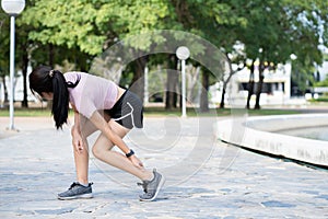 Asian woman runner holding his sports leg injury, muscle painful during training. Asian runner having calf ache and problem after