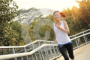 Asian woman running at park footbridge