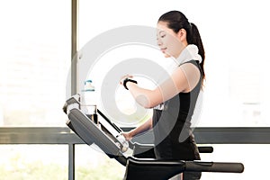 Asian woman running treadmill use smartwatch check pulse rate