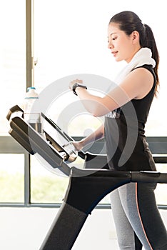 Asian woman running treadmill use smartwatch check pulse rate