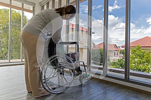 Asian woman`s daughter take care of her senior old mother patient in wheelchair and support her with love and care