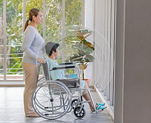 Asian woman`s daughter take care of her senior old mother patient in wheelchair and support her with love and care