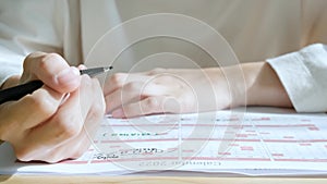 Asian woman`s hand who use a black pen to take notes and put the schedule on the calendar to plan work and meeting schedule before