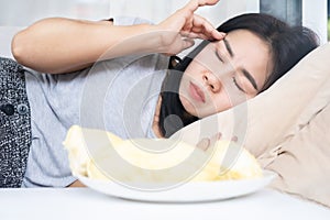 Asian woman's post-Durian overindulgence experiencing headache and dizziness due to excessive consumption