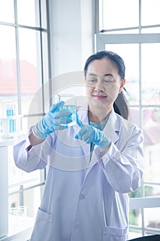 Asian woman scientist look at beaker in her hand