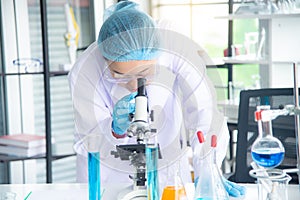 Asian woman scientist, researcher, technician, or student conducted research or experiment by using microscope in laboratory