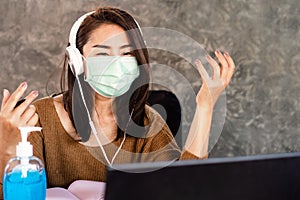 Asian woman in self quarantine for covid-19 or Coronavirus pandemic work and video conference from home wearing protective mask