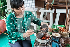 Asian woman selling herbal medicine pouring herbal concoctions into a pot