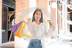 Asian woman shopaholic smiling with many colorful shopping bags and holding credit card for payment