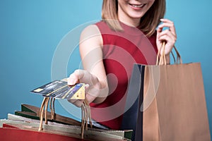 Asian woman with shopping bags showing credit card in hands.