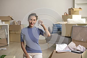 Asian woman showing keys in new house, smiling and looking at camera